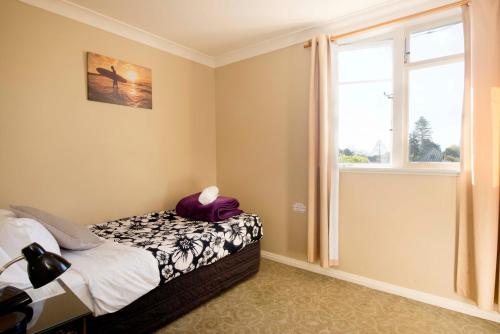 a bedroom with a bed and a window at The Prince Albert Backpackers & Bar in Nelson