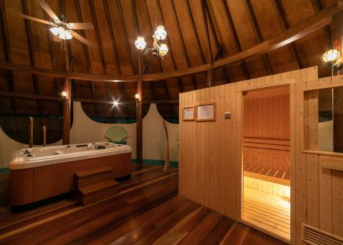 a large bathroom with a tub and a wooden ceiling at Fihalhohi Maldives in South Male Atoll