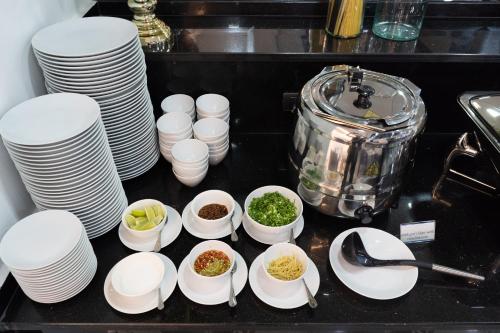 a kitchen counter with white plates and bowls of food at SureStay Hotel by Best Western Vientiane in Vientiane