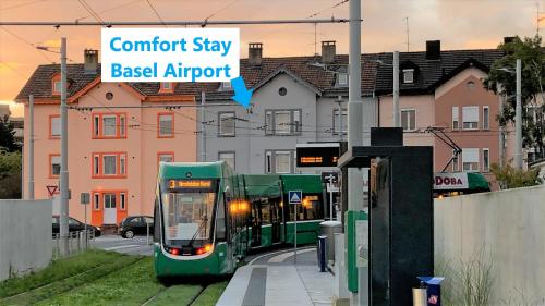 a green bus is stopped at a train station at Comfort Stay Basel Airport 1B46 in Saint-Louis