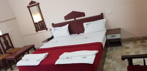 a bedroom with a large bed with red and white sheets at Hotel Nuhman in Kondotti