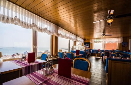 uma sala de jantar com mesas, cadeiras e janelas em Hotel Panorama Garni em Helgoland