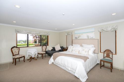 a white bedroom with a large bed and a couch at Daffodil Bed and Breakfast in Hamilton
