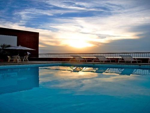 薩爾瓦多的住宿－Sol Victoria Marina Lofts，一个带椅子和遮阳伞的游泳池,并可欣赏日落美景