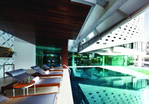 a pool in a building with chairs and a table at LiT BANGKOK Hotel in Bangkok