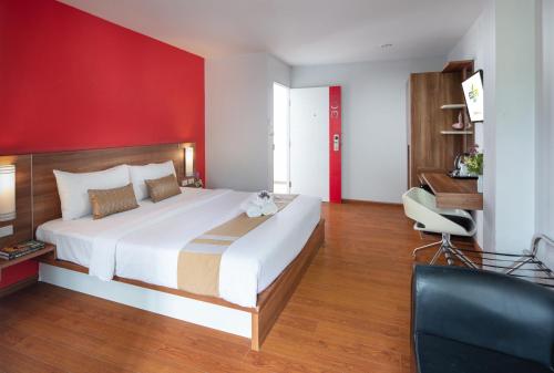 ein Schlafzimmer mit einem großen Bett mit einer roten Wand in der Unterkunft Eco Inn Prime Trang in Trang