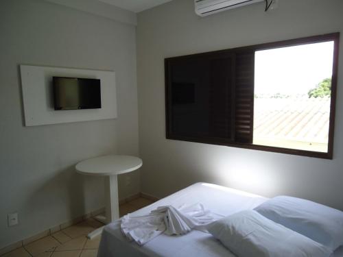 a bedroom with a bed and a window and a table at Big Executive Hotel in Araguari