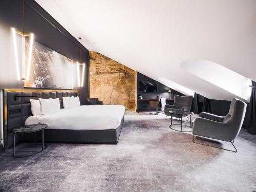a bedroom with a large bed and two chairs at Hotel Pacai, Vilnius, a Member of Design Hotels in Vilnius
