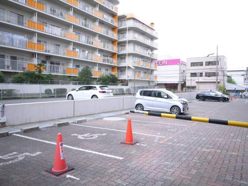 a parking lot with cars parked in front of a building at U-Community Hotel in Osaka