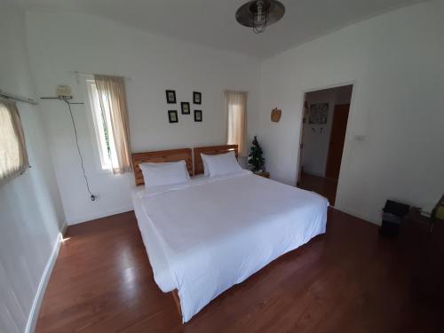 a bedroom with a large white bed and wooden floors at Terrua Main Ten Villa Garden in Suan Phung