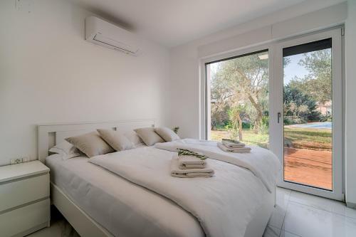 a white bedroom with a large bed and a large window at Villa Čimić in Krk