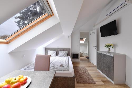 a white attic bedroom with a bed and a tv at Villa Oliver 2 Siófok in Siófok