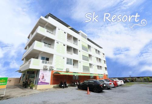 a tall white building with cars parked in a parking lot at sk resort in Bangkok
