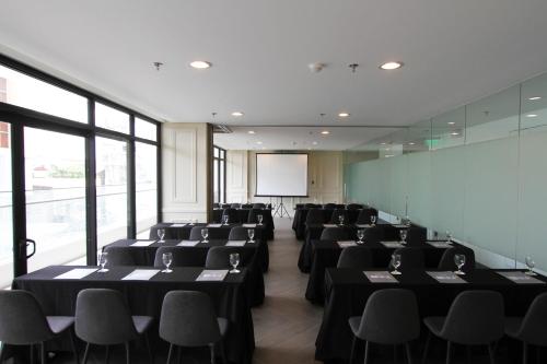 a conference room with black tables and chairs and a screen at Privato Makati in Manila