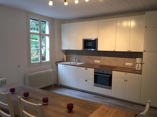 a kitchen with white cabinets and a wooden table at Maison Riviére in Monschau