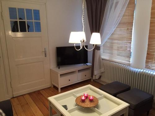 ein Wohnzimmer mit Tisch und Fernseher in der Unterkunft Maison Riviére in Monschau