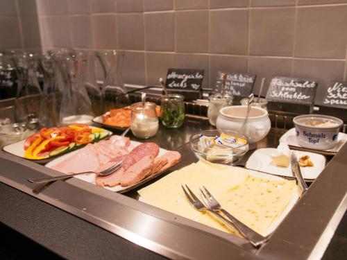 a kitchen counter with meat and vegetables on a table at Hotel Landhafen in Niebüll