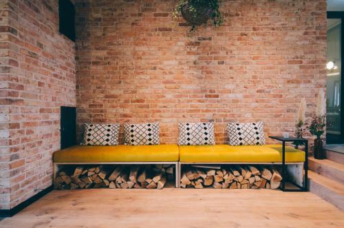 a yellow bench against a brick wall with fire wood at Hotel Landhafen in Niebüll