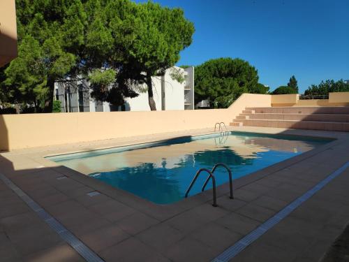 - une piscine à côté des escaliers et des arbres dans l'établissement Les rives du lac, au Grau-du-Roi