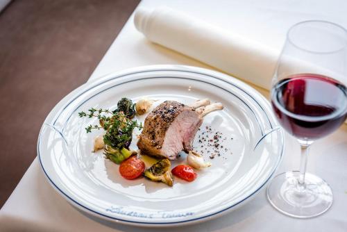 a plate of meat and vegetables next to a glass of wine at Landhaus Tanner in Waging am See