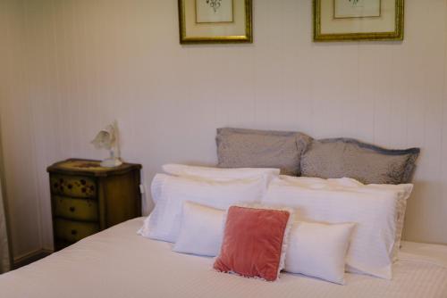 a bed with white pillows and a red pillow on it at Hanging Tree Wines in Pokolbin