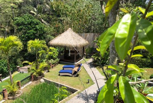 a garden with a gazebo and blue lounge chairs at Puri Kasih Gottlieb in Ubud