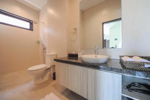 a bathroom with a sink and a toilet and a mirror at Villa Rindik Sanur in Sanur