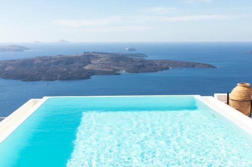 a swimming pool with a view of an island at The Tsitouras Collection in Firostefani