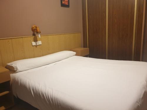 Un dormitorio con una cama blanca con un osito de peluche en la pared en Hostal El Descanso, en Madrid