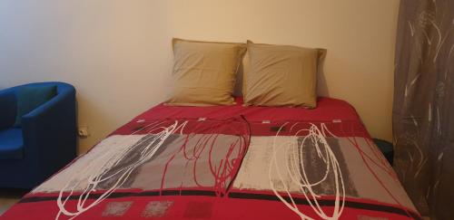 1 cama con manta roja y 2 almohadas en T1 tout confort 2, en Sainte-Clotilde