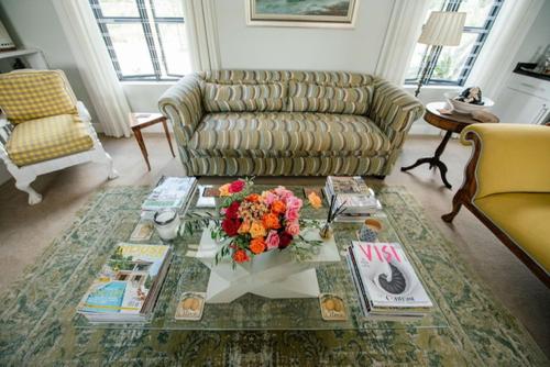 a living room with a couch and a table with flowers on it at Vineyard Views Country House in Riebeek-Kasteel