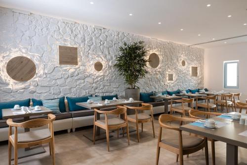 a restaurant with tables and chairs and a stone wall at Santorini Kastelli Resort in Kamari