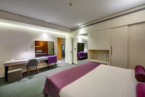 una camera d'albergo con un grande letto e una scrivania di The Act Hotel Sharjah a Sharjah