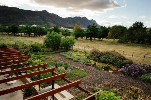 a garden with wooden benches and a garden with flowers at Vineyard Views Country House in Riebeek-Kasteel