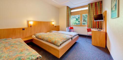 une chambre d'hôtel avec un lit et une télévision dans l'établissement Sport Resort Fiesch, Garni Aletsch, à Fiesch