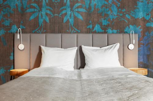 a bedroom with a bed with two pillows and a wallpaper at Leśny Dwór in Sulęczyno