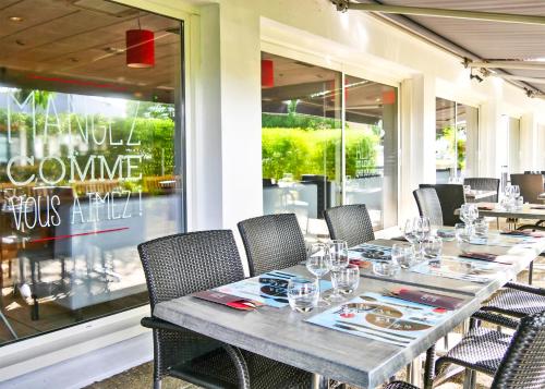 a table in a restaurant with chairs and a window at ibis Laval Le Relais D'Armor in Laval
