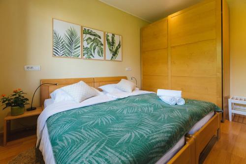 a bedroom with a bed with a green and white comforter at Apartmaji Koman in Bled