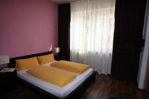 a bedroom with a bed with yellow sheets and a window at Stadthotel Kleiner Berg in Friedrichshafen