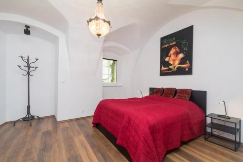 Schlafzimmer mit einem roten Bett und einem Kronleuchter in der Unterkunft Budyne Apartment II. in Budyně nad Ohří