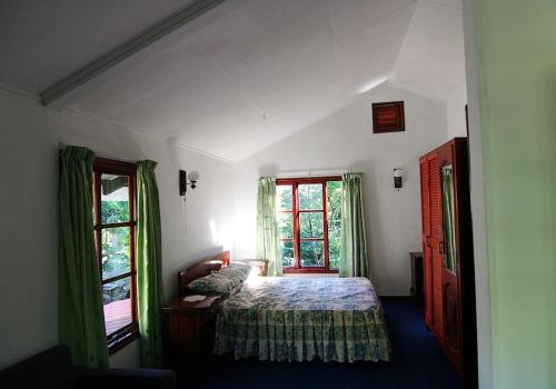 a bedroom with a bed and two windows at La Rocaille in Baie Lazare Mahé