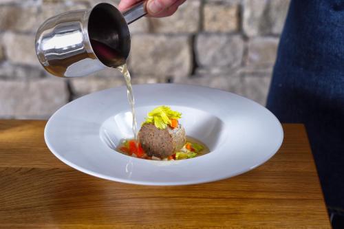 a person pouring wine into a plate of food at HOTEL PECR WELL in Pec pod Sněžkou
