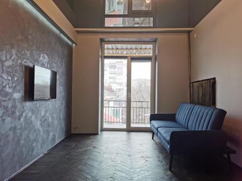 un soggiorno con divano blu e finestra di Loft style apartments in the center a Sumy