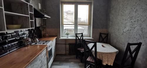 a kitchen with a table and chairs and a window at Loft style apartments in the center in Sumy