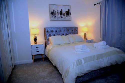 a bedroom with a large white bed with two lamps at A Modern, Comfy Newly Remodeled 2bd House in Barking