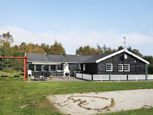 una gran casa negra con un parque infantil delante de ella en 15 person holiday home in Hals, en Hals