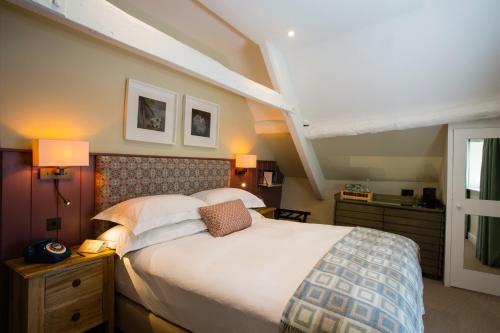 una camera da letto con un grande letto con lenzuola e cuscini bianchi di The Boot at Barnsley a Cirencester