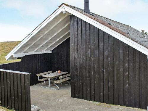 un edificio negro con mesa de picnic y techo en 6 person holiday home in Vejers Strand, en Vejers Strand