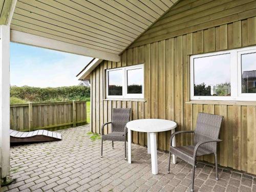een patio met een tafel en stoelen en een hek bij 8 person holiday home in Ringk bing in Søndervig