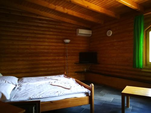 a bed in a wooden room with a television at Tornyos Panzió és Étterem in Matrafured